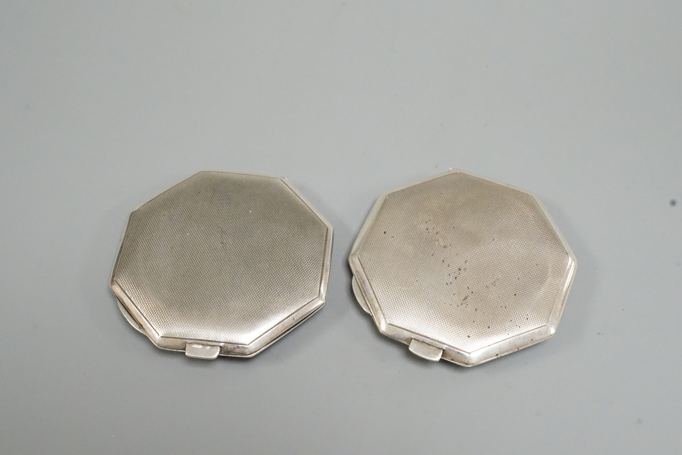 A pair of George VI part engine turned silver and enamel octagonal compacts, with coronet appliqués, John William Barrett, Birmingham, 1941, 77mm.